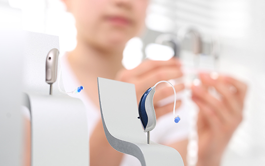 Moderne Hörgeräte werden in einem Hörakustik-Fachgeschäft von einer Person präsentiert.