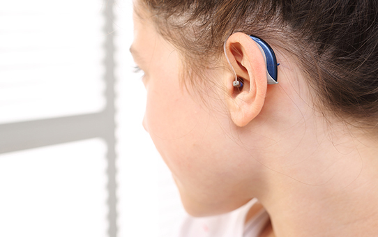 Mädchen mit Hörgerät im Ohr zur Unterstützung des Hörvermögens und barrierefreien Kommunikation.